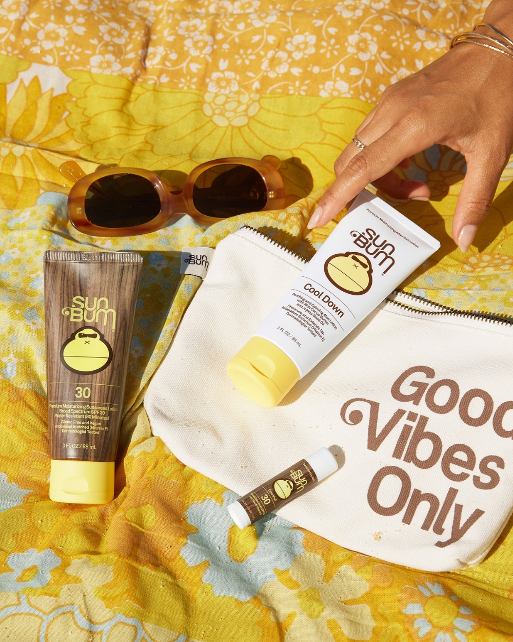Sun Bum Day Tripper sunscreen travel kit on beach towel lifestyle image