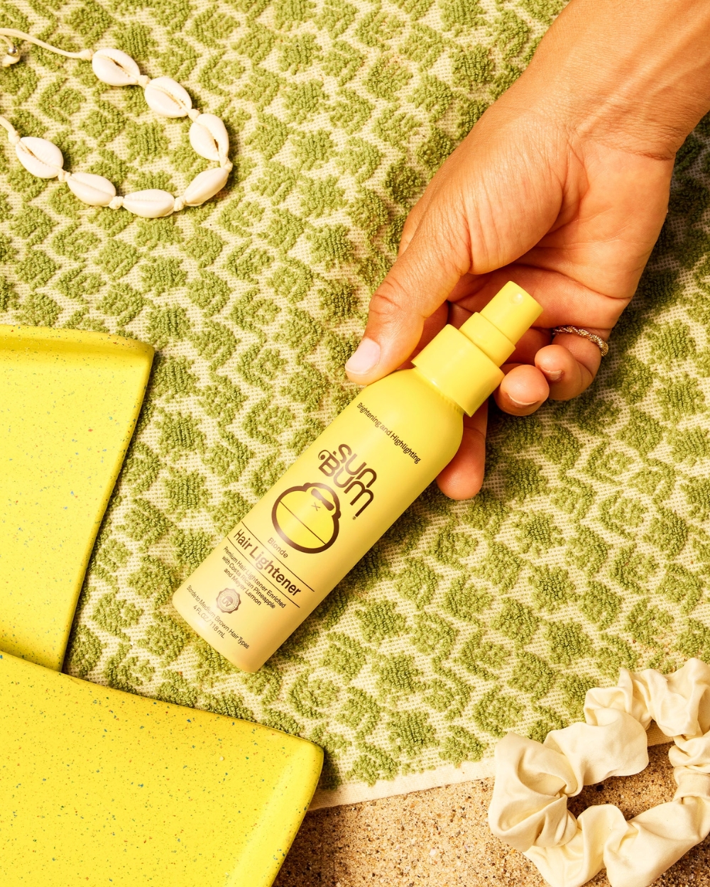 “Sun Bum Blonde Hair Lightener 118mL lifestyle shot on beach towel in sunlight”